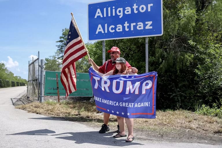 Trump supporters posing under "Alligator Alcatraz" road sign