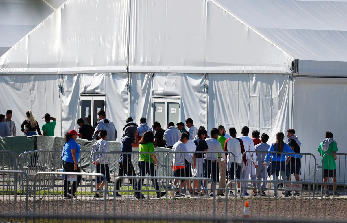 Children standing in line outside a detention tent