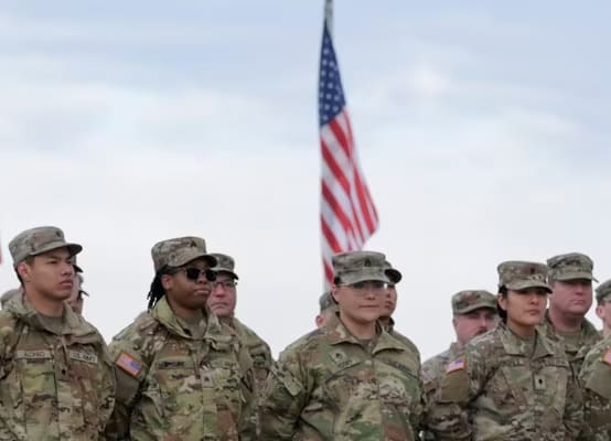 Troops stand in front of an American Flag